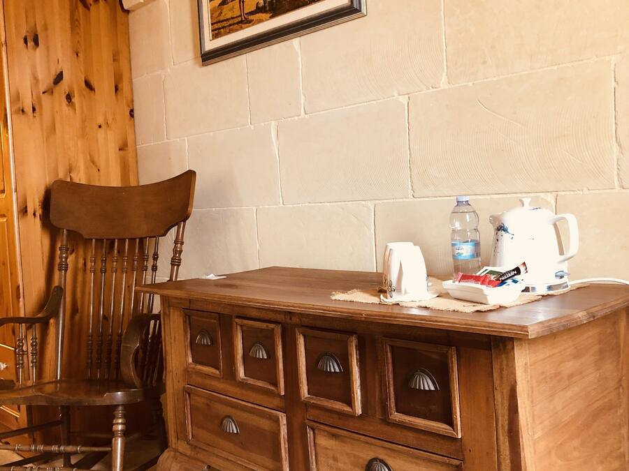 A wooden desk with drawers, a chair, a framed picture on the wall, and a tiled floor.