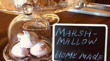 Una presentación de postres bajo una campana de cristal y un cartel que indica 'Marshmallow Hecho en Casa'.