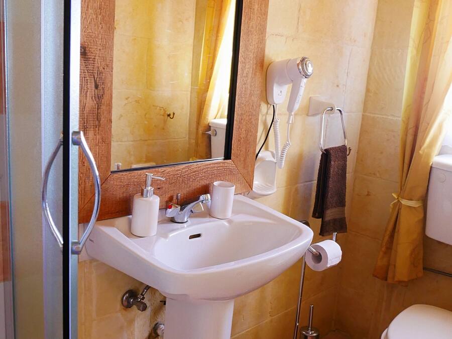 A bathroom with a white sink, a mirror, a hairdryer, and a toilet.