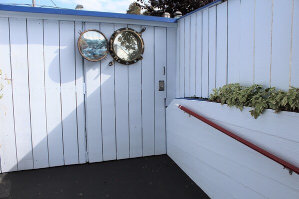 A white wooden wall with two round mirrors and a red handrail.