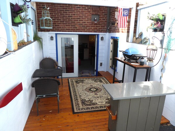A patio with a wooden floor, a small rug, and a metal table. - PORTHOLE: Private, Peaceful with a locked patio for relaxing and bikes. (Port Angeles)
