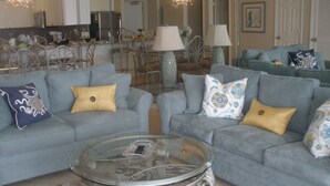 A living room with two grey sofas, a glass coffee table, and a patterned rug. - SUGAR WHITE SAND! RIGHT ON THE BEACH!! GREAT VIEWS!! FAMILY FUN!!
#1815 DESTIN (Destin)