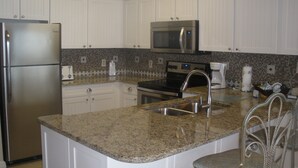 A kitchen with white cabinets, a stainless steel refrigerator, a microwave, an oven, a sink, and a granite countertop. - SUGAR WHITE SAND! RIGHT ON THE BEACH!! GREAT VIEWS!! FAMILY FUN!!
#1815 DESTIN (Destin)