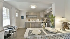 A modern kitchen with a dining area, stainless steel appliances, and a marble countertop. - Shasta Serenity A cozy cottage in Downtown Mt Shasta (Mt Shasta)