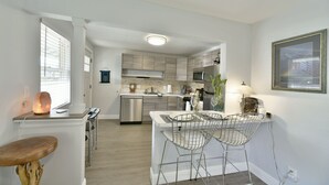 A modern kitchen with a central island, bar stools, and a dining table. - Shasta Serenity A cozy cottage in Downtown Mt Shasta (Mt Shasta)