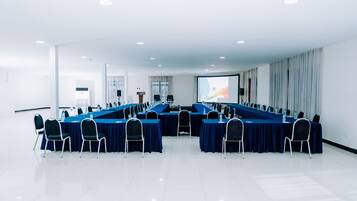Un salón de conferencias con una larga mesa y sillas, una pantalla de proyector y una pizarra.