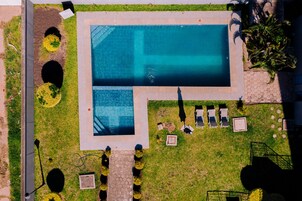 Una piscina al aire libre, sombrillas, sillones reclinables de piscina