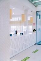 Un área de recepción con un mostrador blanco, iluminación colgante y una puerta azul.