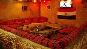 A room with a large, striped sofa set, a television on the wall, and a flag decoration. - Al Baeirat hotel (Luxor)