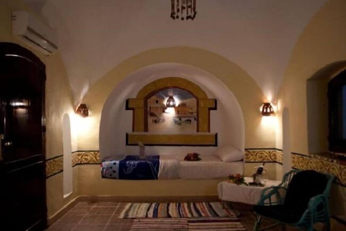 Ein Schlafzimmer mit gewölbter Decke, einem Bett mit Kopfteil, einem Nachttisch, einem Stuhl und Blick auf die Stadtlandschaft.