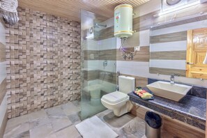 A modern bathroom with a glass-enclosed shower, a toilet, and a sink with a marble countertop. - Grand Krisa Resort & Spa (Manali)