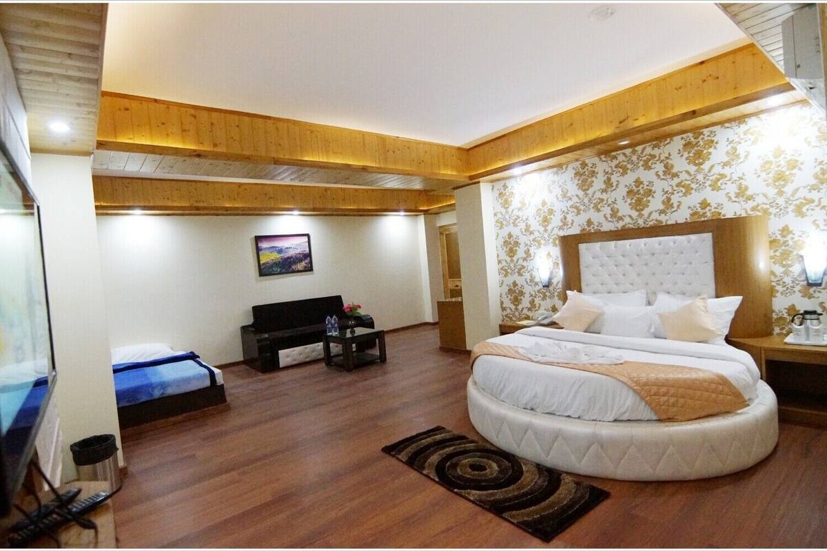 Un dormitorio con una cama grande, un sofá, un televisor y una mesita.