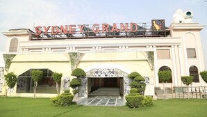 The Sydney Grand hotel entrance with a prominent sign, a grand archway, and well-maintained landscaping. - Sydney Grand Hotel & Resort (New Delhi)