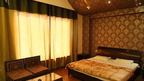A bedroom with a large bed, a sofa, and a coffee table. - Sydney Grand Hotel & Resort (New Delhi)