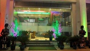 A hotel entrance with a glass facade, steps leading up to the door, and two illuminated Christmas trees. - Sydney Grand Hotel & Resort (New Delhi)