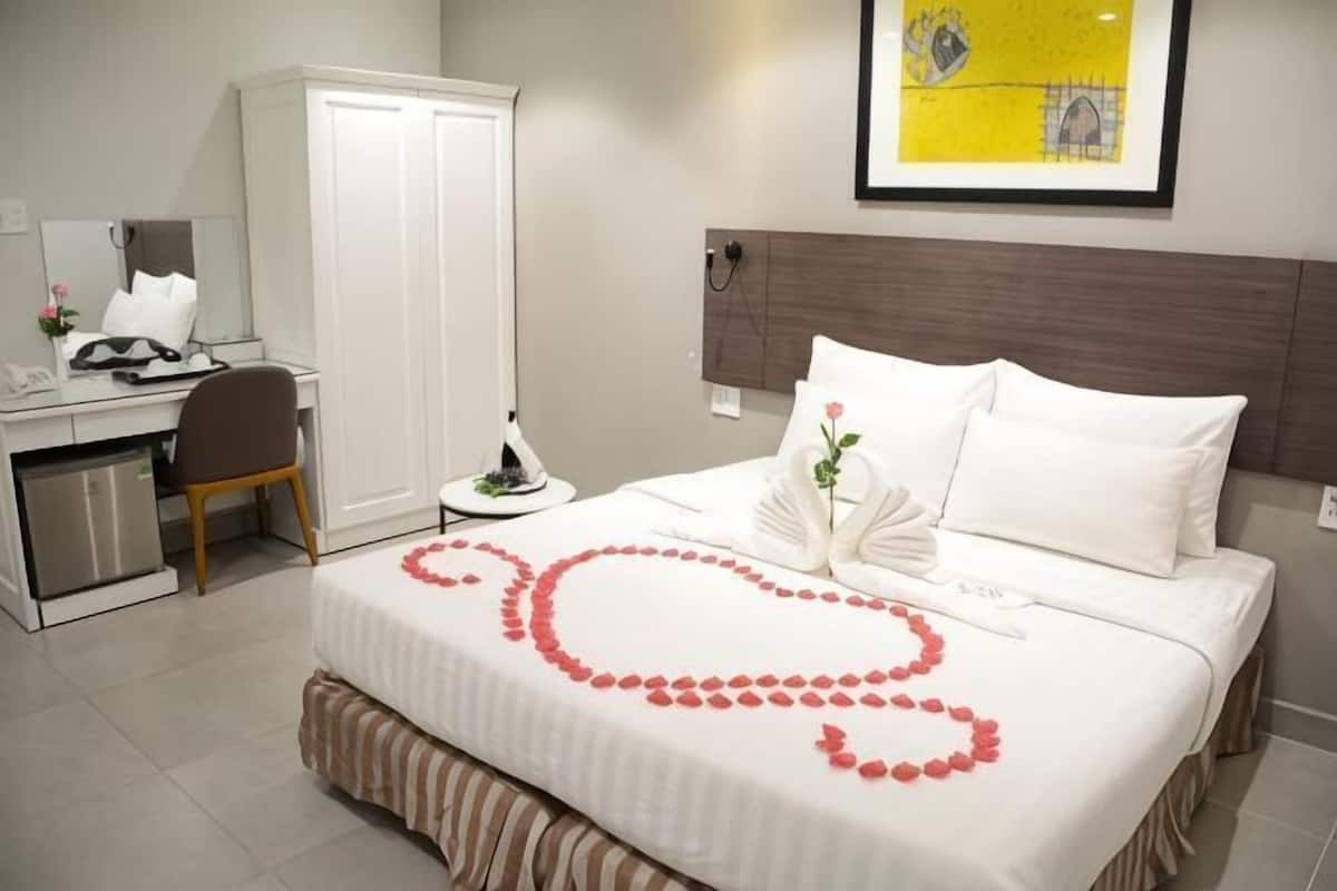 Una habitación de hotel con cama, escritorio, armario y un cuadro en la pared.