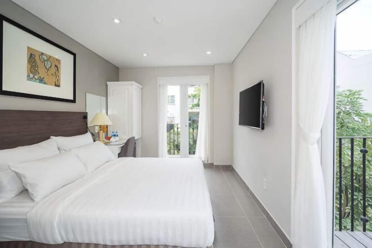 Un dormitorio con una cama grande, un televisor montado en la pared y un balcón con vistas.