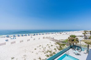 Une vue sur la plage avec un espace piscine, comprenant des chaises longues et des parasols.