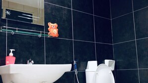 Un baño con lavamanos blanco, inodoro y espejo sobre el lavamanos.