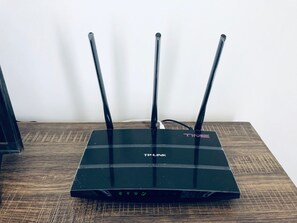 A TP-Link router with three antennas on a wooden surface. - Cozysoho-Cyberjaya,fit 5 paxs,1 bedroom with parking (Cyberjaya)