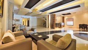 A spacious lobby with a reception desk, seating area, and a staircase leading to upper floors. - Westend Inn (New Delhi)