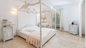 Una cama con dosel, una mesita de noche con lámpara y un aparador con espejo.