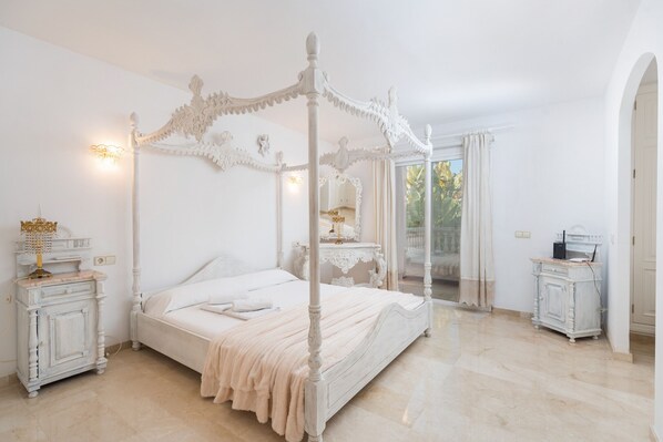 Un lit à baldaquin, une table de chevet avec une lampe et une commode avec un miroir.