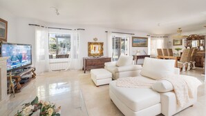 Un salón amplio con un sofá blanco grande, televisión y chimenea.