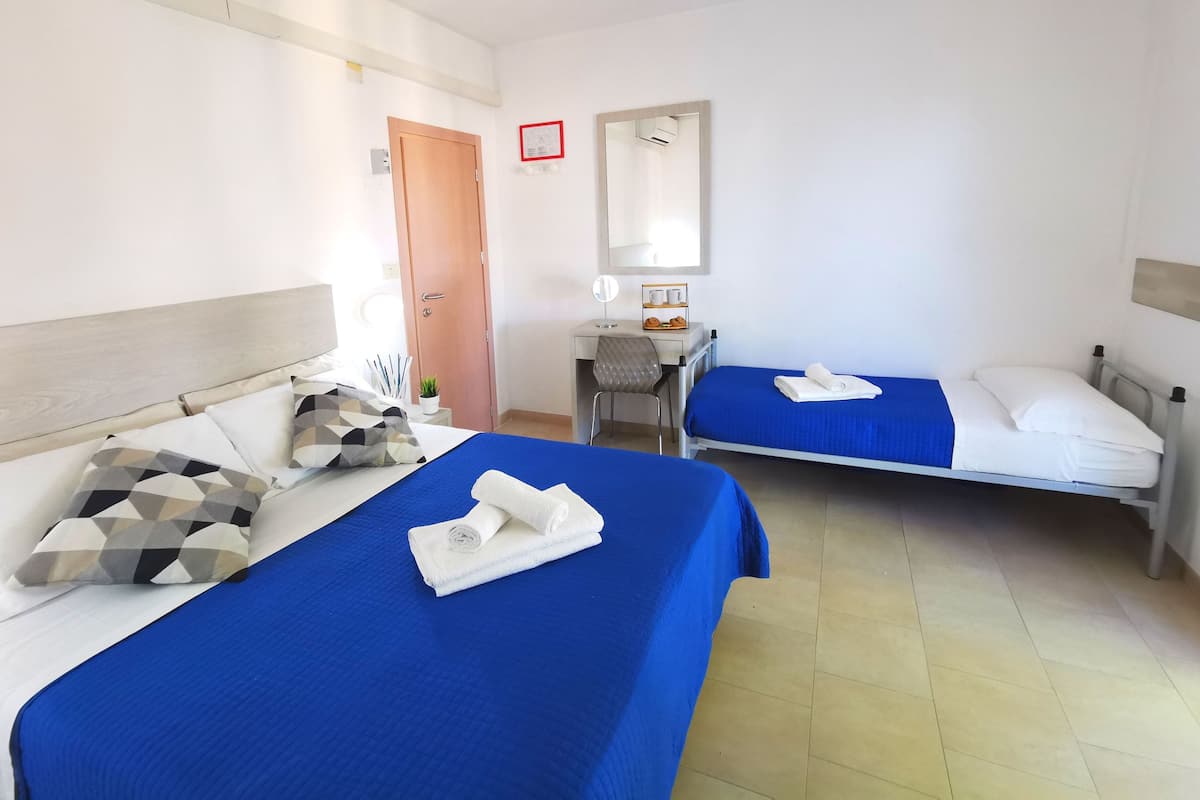 A hotel room with two beds, a desk, a chair, and a mirror.