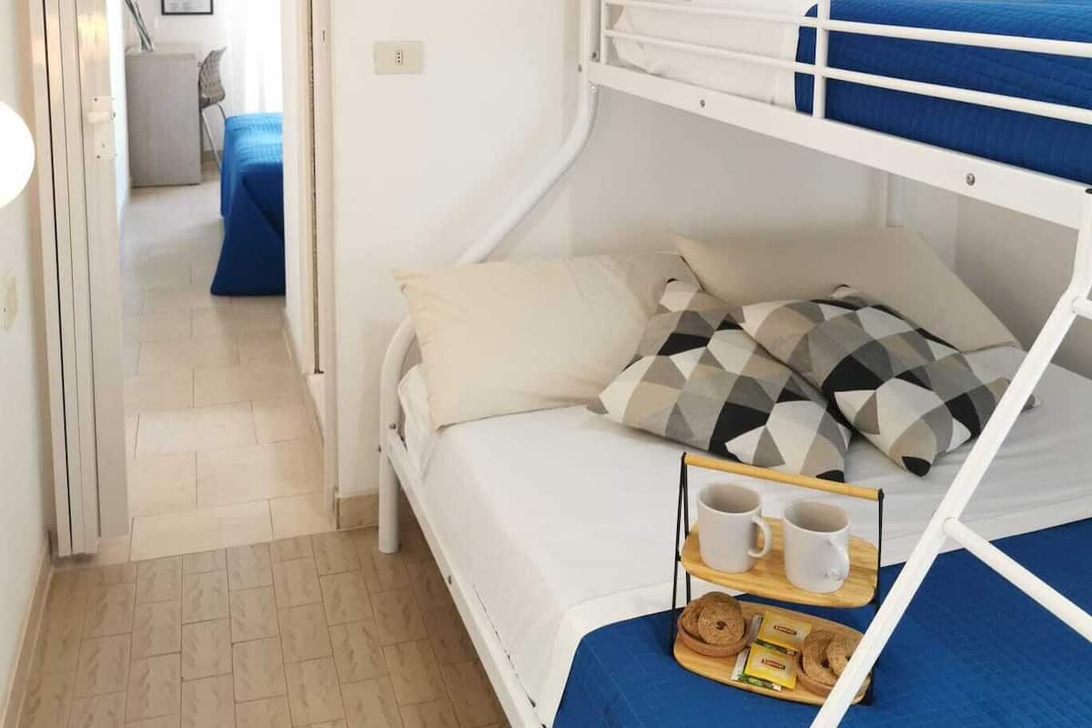 A bunk bed room with a TV mounted on the wall, a tray with snacks and a cup, and a door leading to another room.
