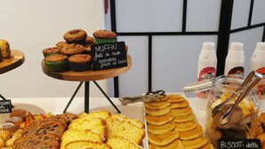 A variety of baked goods including muffins, cupcakes, and pancakes displayed on a table with labels indicating flavors and ingredients. - Hotel Bellini (Riccione)