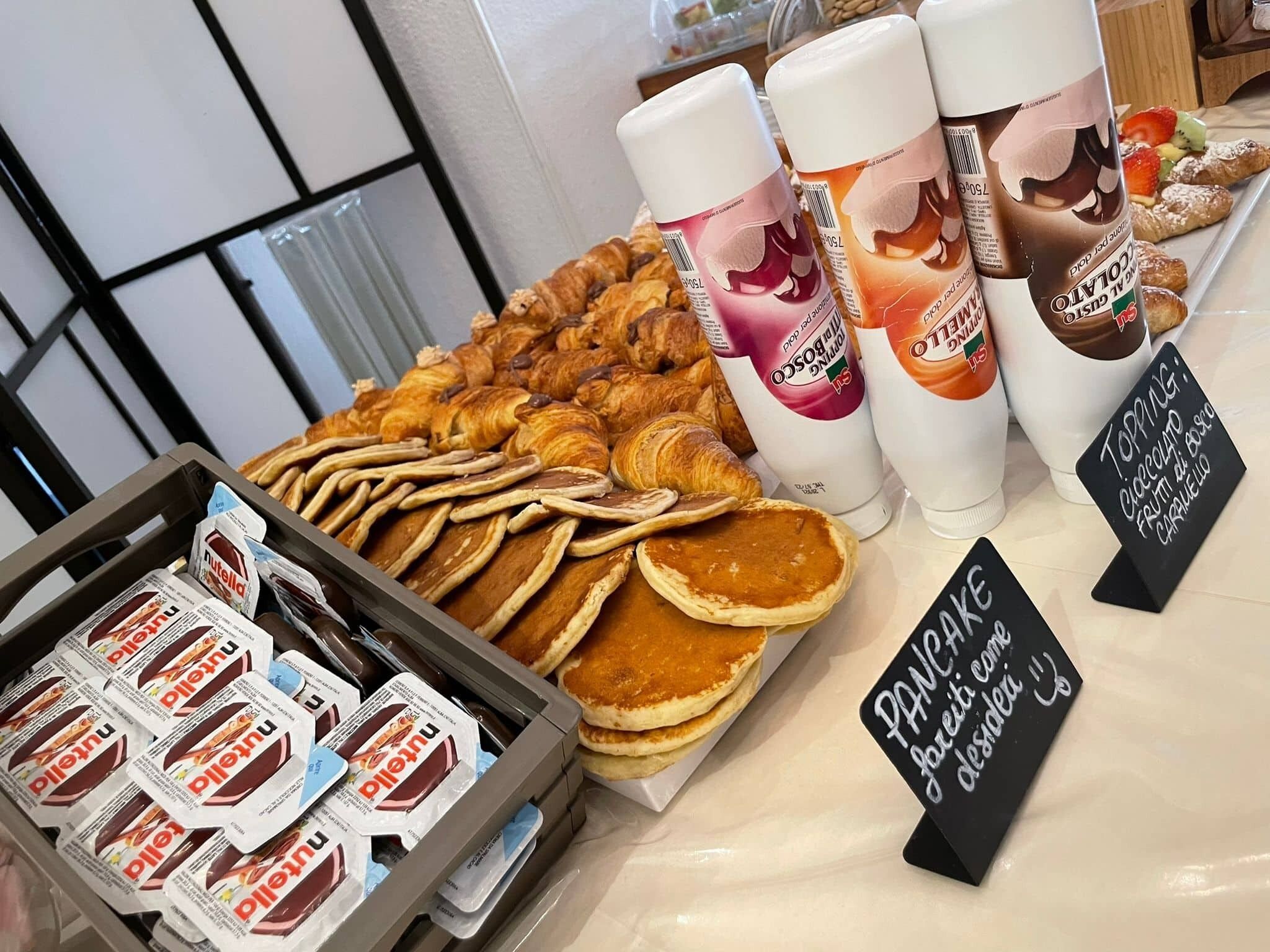Eine Auswahl an Gebäck, Nutella-Portionen und Milchkartons mit verschiedenen Geschmacksrichtungen in einer Bäckerei.