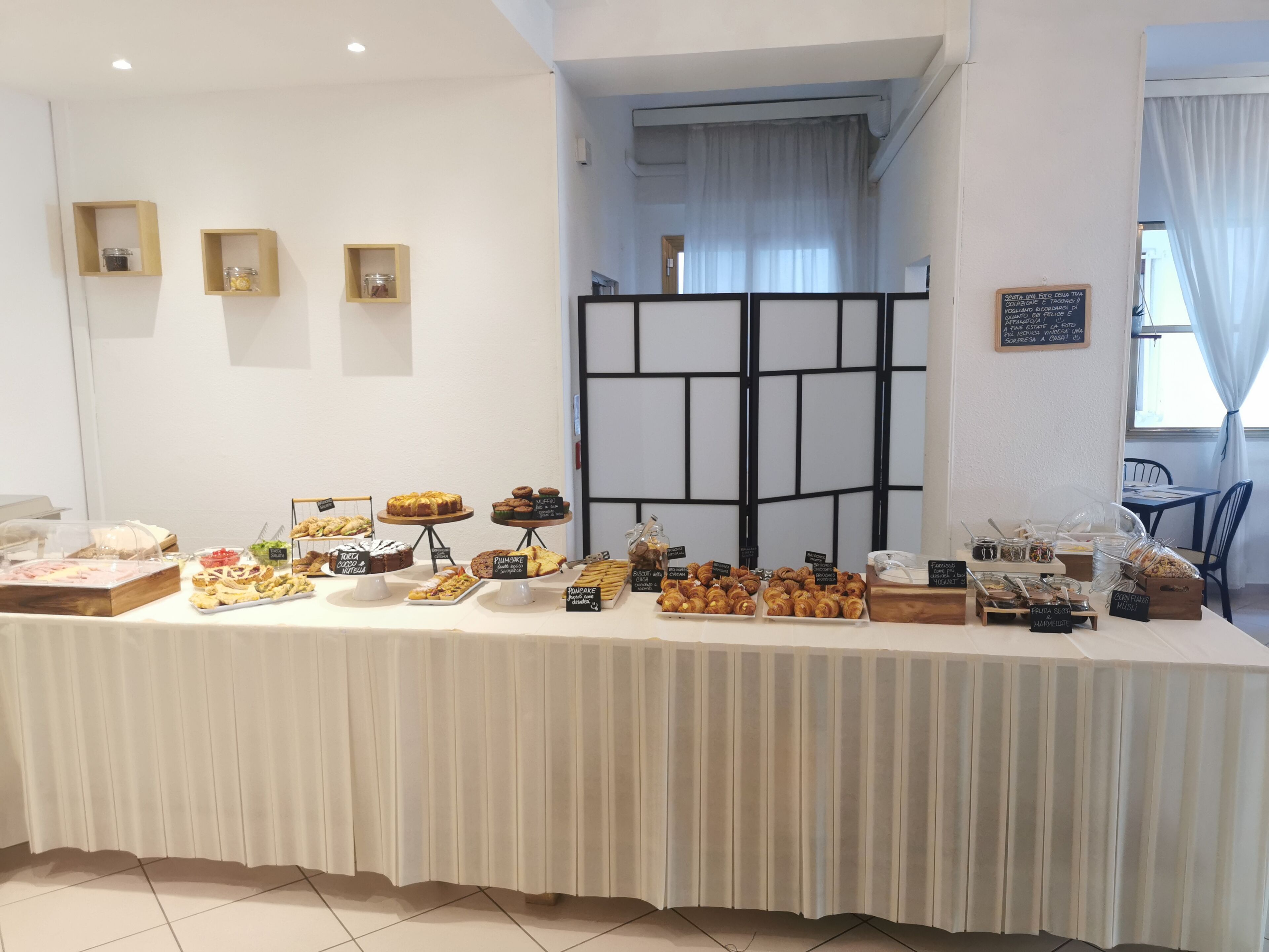 A buffet table with various food items and a blackboard with menu information.