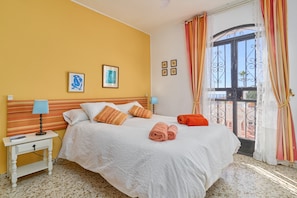 A bedroom with a bed, bedside tables, a window with curtains, and wall art.