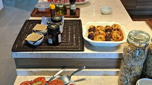 Un buffet proposant une variété de plats, notamment des viandes, des fromages et des pâtisseries, ainsi que des condiments et des ustensiles.