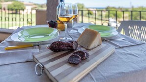 A table set with plates, a bottle of wine, a cheese, and sliced meats on a wooden board. - Holiday apartment surrounded by nature (Siniscola)