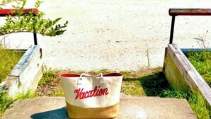 Een strand met een tas met daarop de tekst 'Vacation' in de voorgrond.
