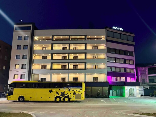 A multi-story hotel with a 'MOTEL' sign, a yellow bus parked in front, and a reception area with a sign reading 'Welcome.' - Hotel Espana (East Sarajevo)