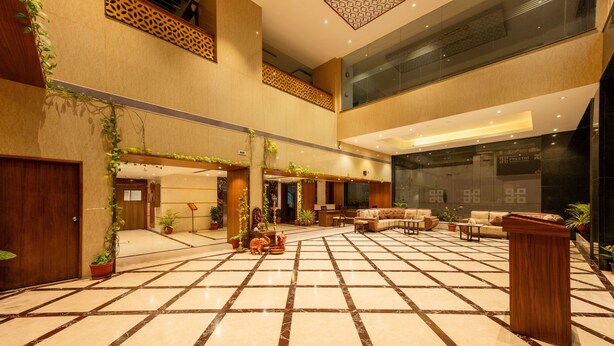 A spacious lobby with a checkered floor, seating area, and potted plants. - Hotel Preethi International (Mysore)