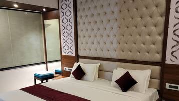 Habitació d'hotel amb un llit gran, un panell de capçalera de fusta i un disseny modern.