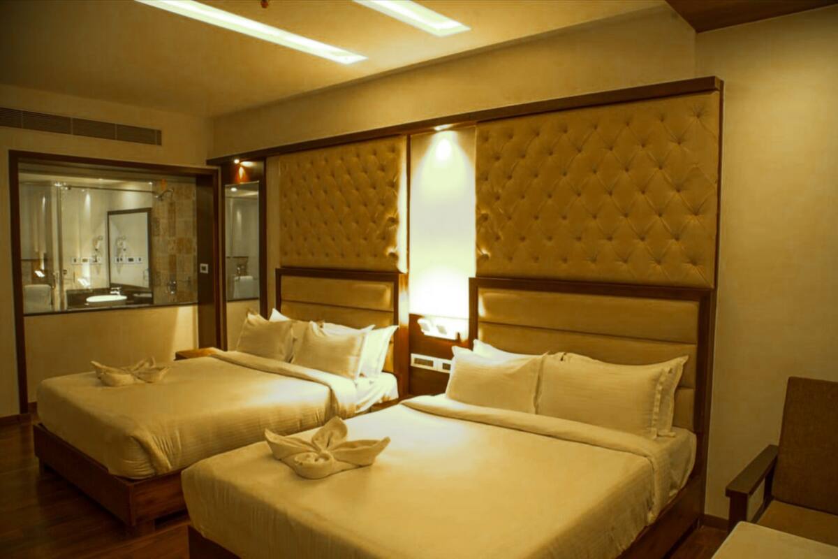 A hotel room with two beds, a large mirror, and a wooden headboard.