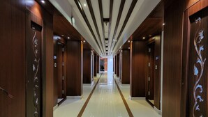 A long, polished hallway with wooden doors and a central strip. - Hotel Preethi International (Mysore)