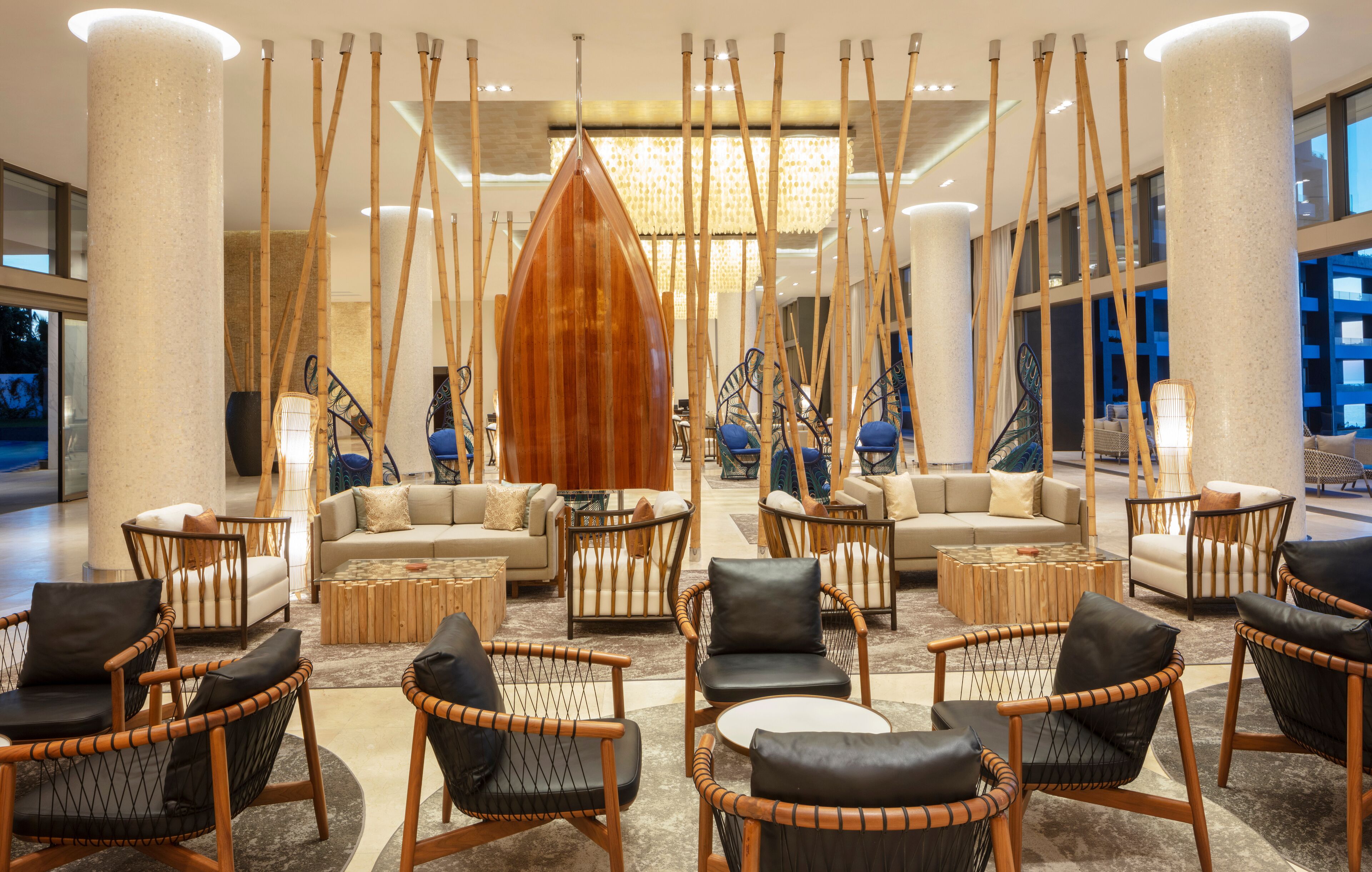 Un vestíbulo espacioso con muebles modernos, incluyendo sofás y sillones, y una gran escultura de madera.
