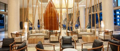 Un vestíbulo espacioso con muebles modernos, incluyendo sofás y sillones, y una gran escultura de madera.