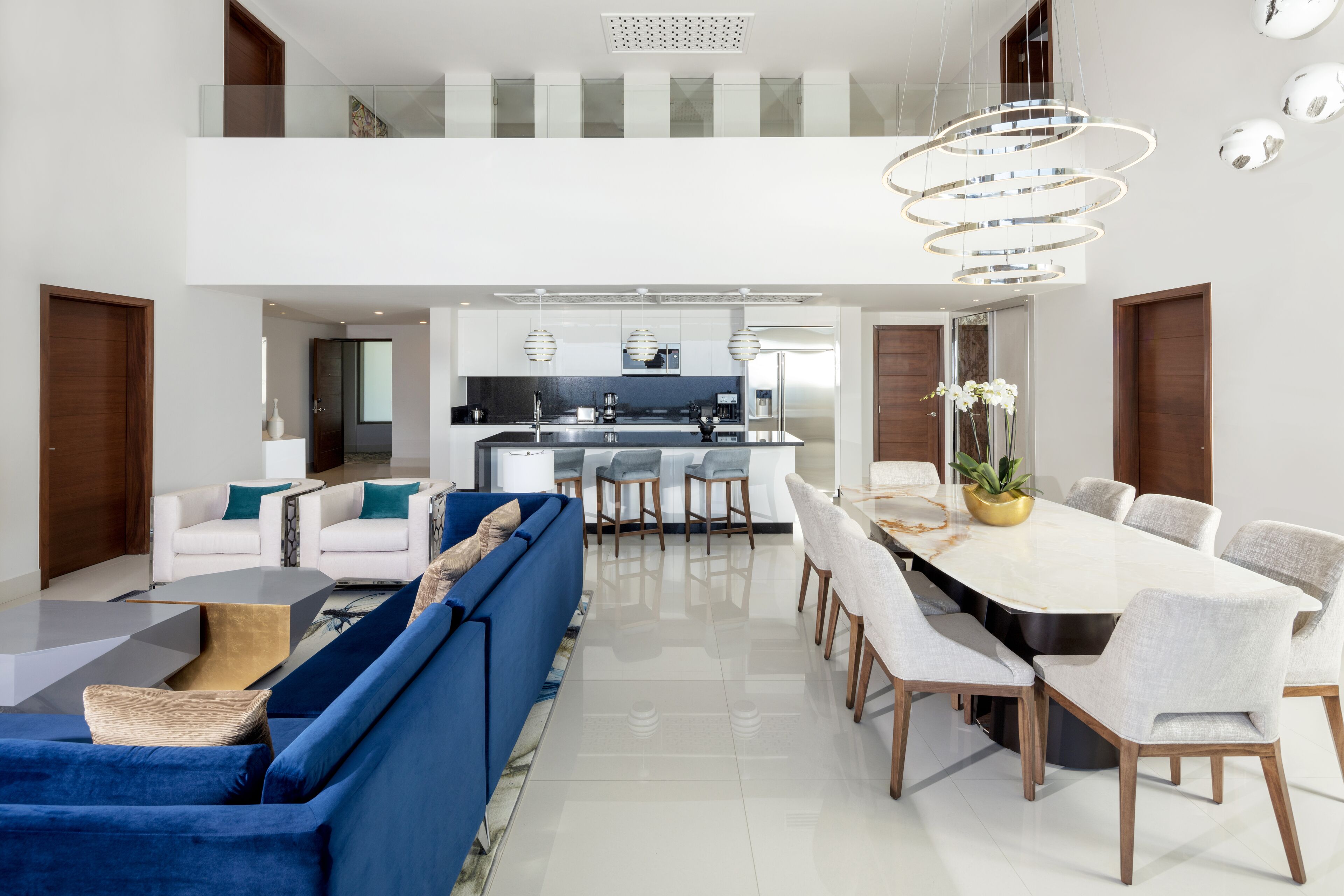 Un salon moderne avec un canapé bleu, une table à manger et des chaises, et une cuisine en arrière-plan.