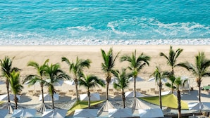 A beach with white umbrellas and palm trees. - Garza Blanca Los Cabos - All Inclusive (Cabo San Lucas)
