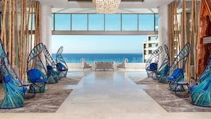 A modern lounge area with hanging chairs and a view of the ocean. - Garza Blanca Los Cabos - All Inclusive (Cabo San Lucas)