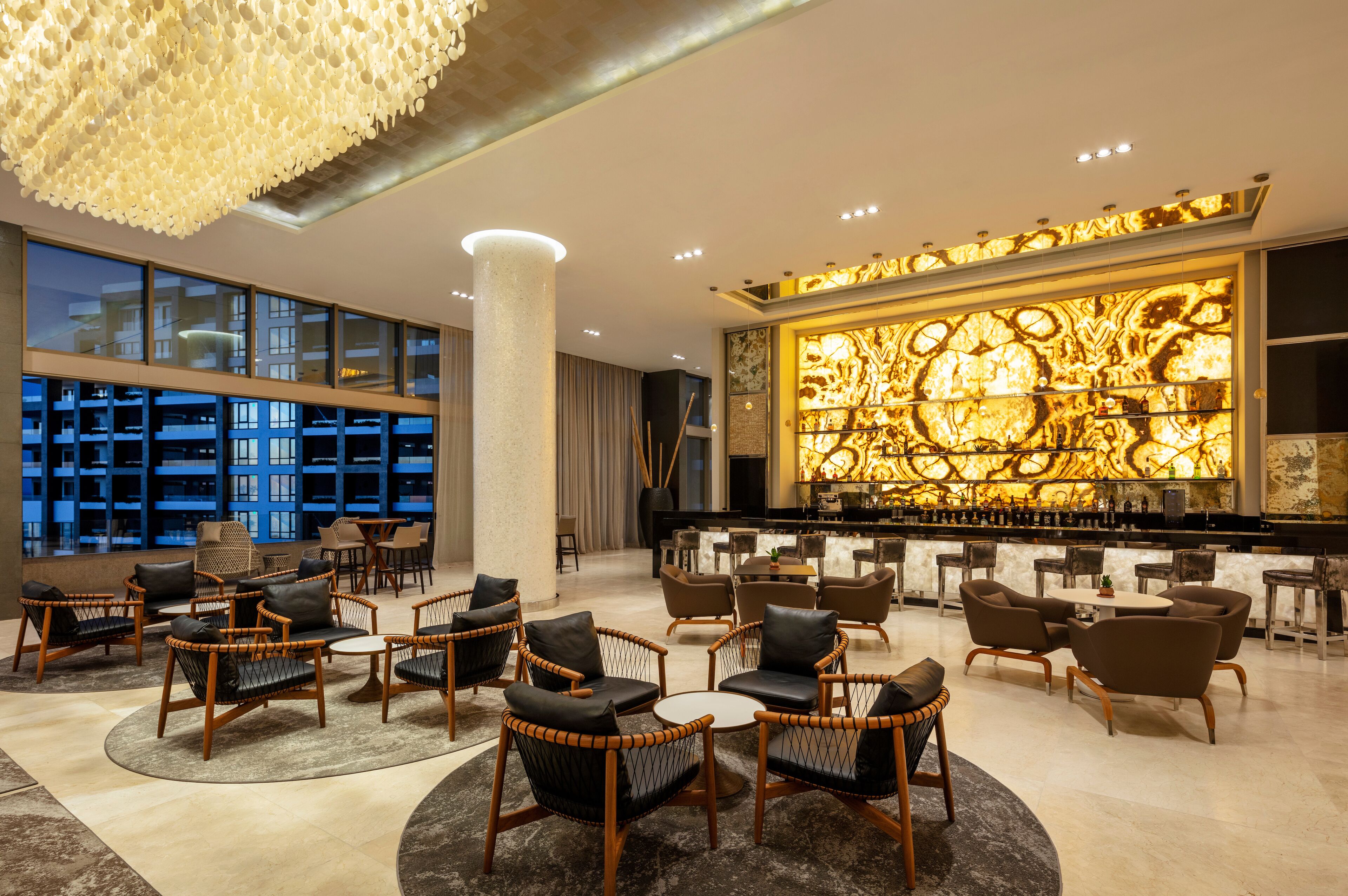 A modern lobby with a bar area, seating arrangements, and large windows.