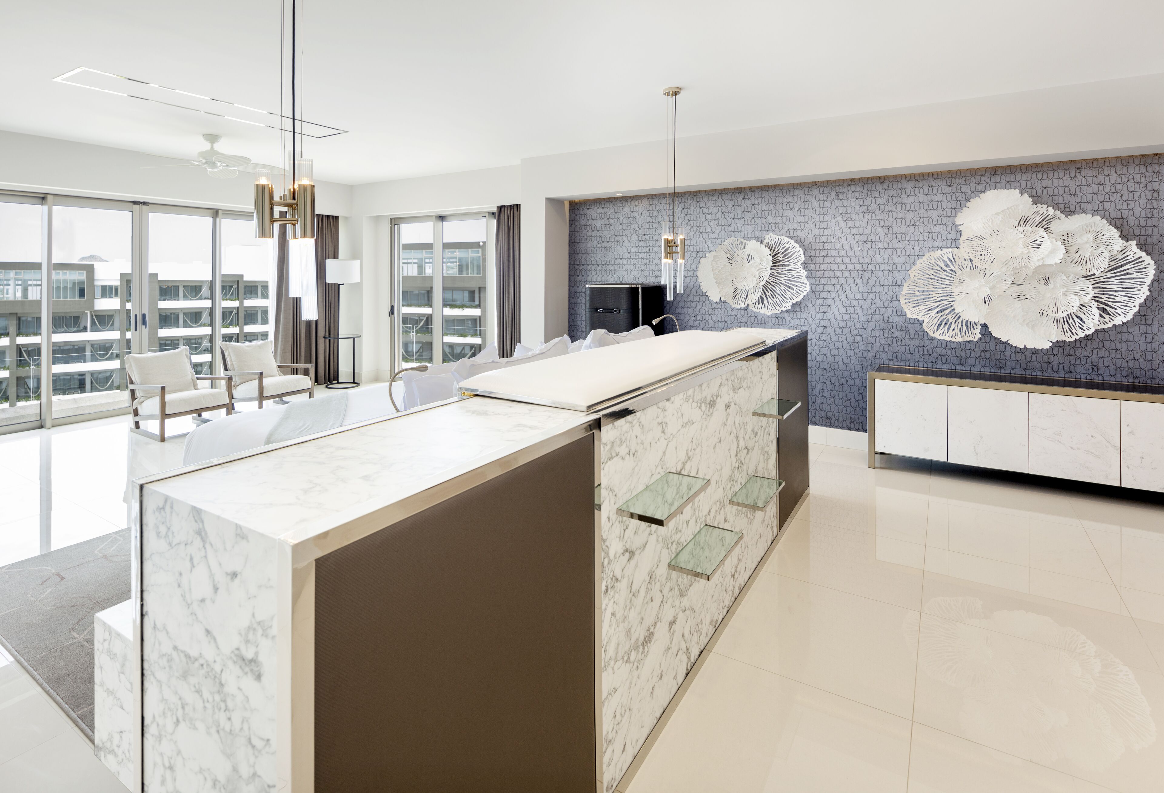 A modern hotel lobby with a marble reception desk, seating area, and decorative wall art.