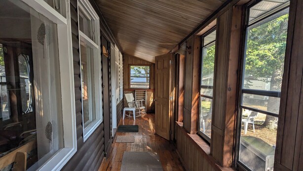 Une cabane en rondins dotée d’un porche couvert, de planchers en bois et de grandes fenêtres.